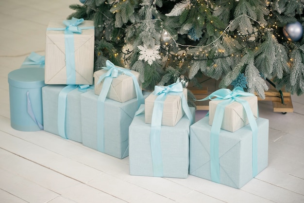 Geschenkboxen unter Weihnachtsbaum auf weißem Holzboden