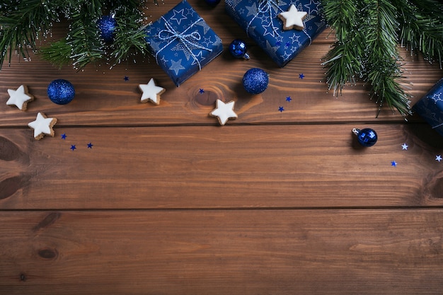 Geschenke, Tannenzweige, blaue Verzierungen auf Holz