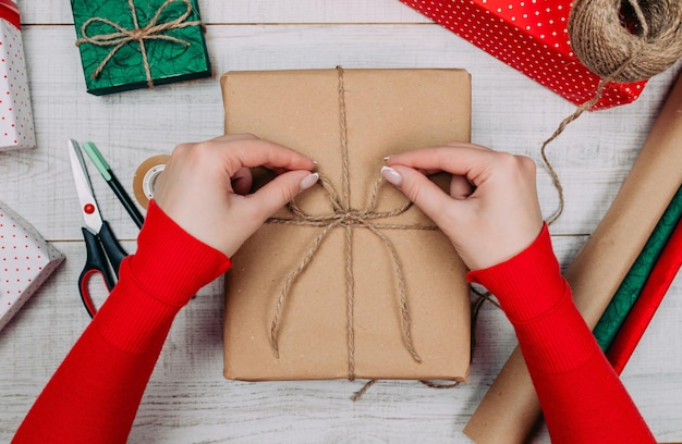 Geschenkpapier. Frau packt Weihnachtsgeschenke zu Hause auf Holztisch.