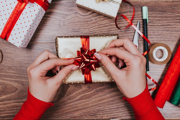 Geschenkpapier. Frau packt Weihnachtsgeschenke zu Hause auf Holztisch.