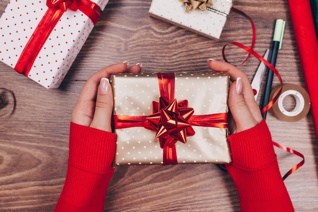 Geschenkpapier. frau packt weihnachtsgeschenke zu hause auf holztisch.