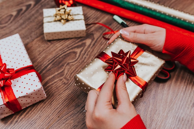 Geschenkpapier. Frau packt Weihnachtsgeschenke zu Hause auf Holztisch.