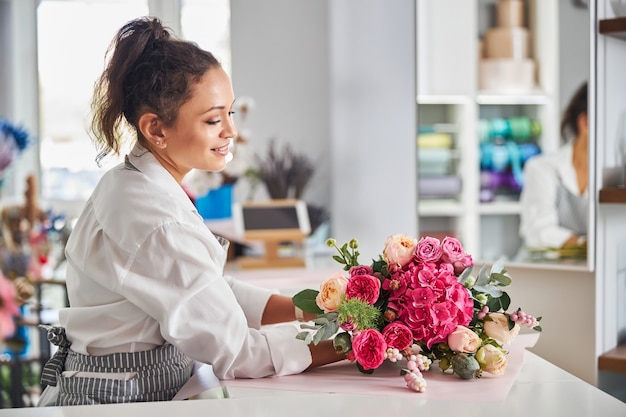 Geschickte Floristin, die einen Blumenstrauß bewundert