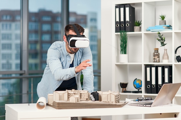 Geschickter männlicher Architekt, der Architekturprojekt mit vr Brille am modernen Büro überprüft.