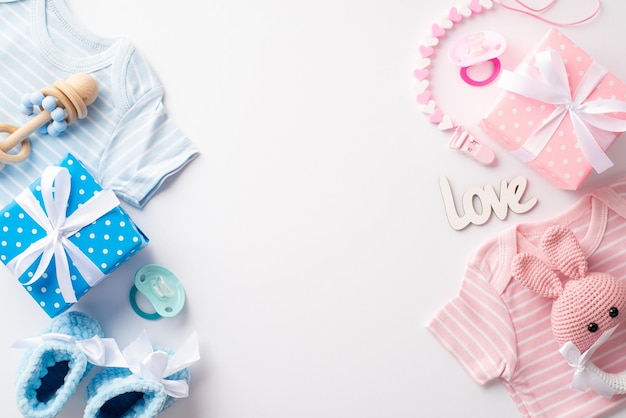 Geschlecht enthüllen Party-Konzept Top-View-Foto von rosa und blau Babykleidung Geschenkkisten gestrickte Hase Rasseln Spielzeug Schuhe Schnuller Zähne Kette Inschrift Liebe isoliert weißer Hintergrund mit Copyspace