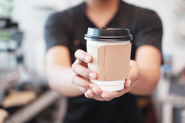 Geschlossen auf der Hand der asiatischen jungen Barista-Frau hält eine Tasse heißen Kaffee im Café