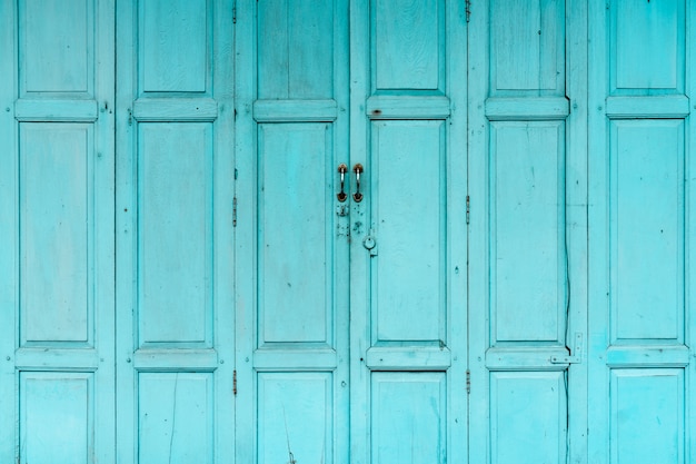 Geschlossene grüne oder blaue Holztür. Abstrakter Hintergrund der Weinlese-Haustür. Verlassenes altes Haus.