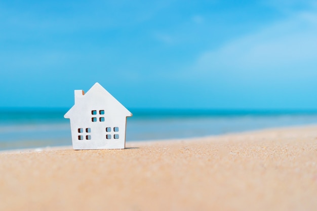 Geschlossene winzige Hauptmodelle auf Sand mit Sonnenlicht und Strandhintergrund.