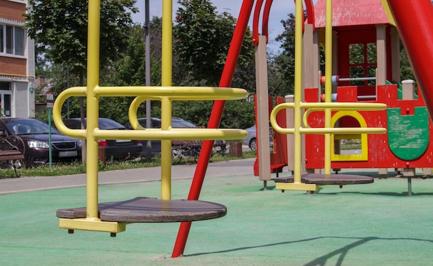 Geschlossener moderner Spielplatz. Sicherheits- und Schutzmaßnahmen gegen COVID-19 im Stadtpark. Baby leere gelbe Metallschaukel im Park ohne Leute. Das Konzept der Kindheit ist vorbei.