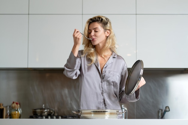 Geschmack und köstliches blondes schönes sexy Mädchen, das in der Küche kocht und Frühstück mit gesundem Essen macht m