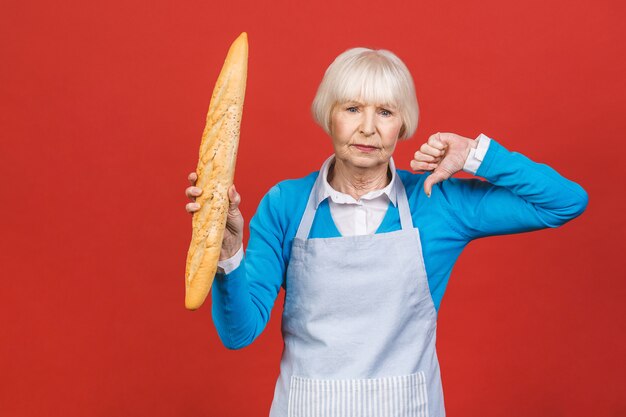 Geschmack von Frankreich. Porträt einer freudigen älteren Frau, die ein frisches köstliches Baguettebrot hält