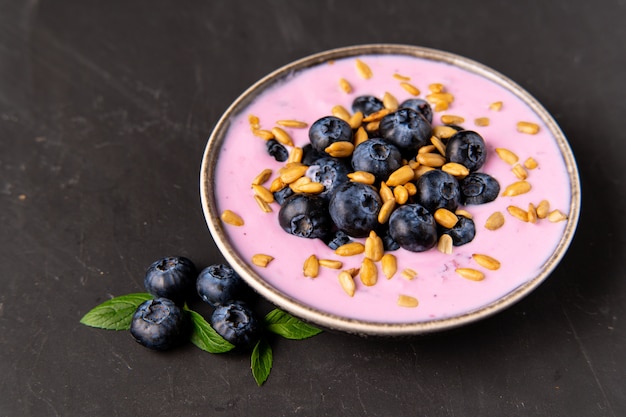 Geschmackvoller frischer Blaubeerjoghurt-Erschütterungsnachtisch in der keramischen Schüssel, die auf schwarzer Tabelle steht. Selbst gemachter Beerensmoothie. Gesundes Essen. Diätessen. Joghurt