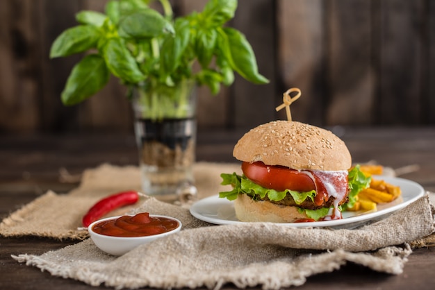 Geschmackvoller Hamburger mit Fleisch und Gemüse gegen einen dunklen Hintergrund. Fast Food. Es kann als Hintergrund verwendet werden