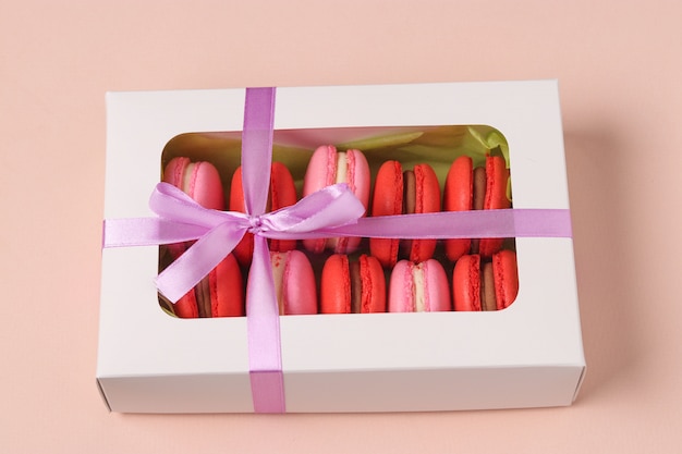 Geschmackvolles süßes Plätzchen macaron, Makrone in einer weißen Geschenkbox auf einem Rosa