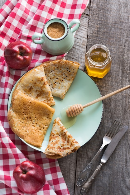 Geschmackvolles traditionelles russisches Frühstück des Pfannkuchens mit Honig auf Platte. Rustikaler Stil.