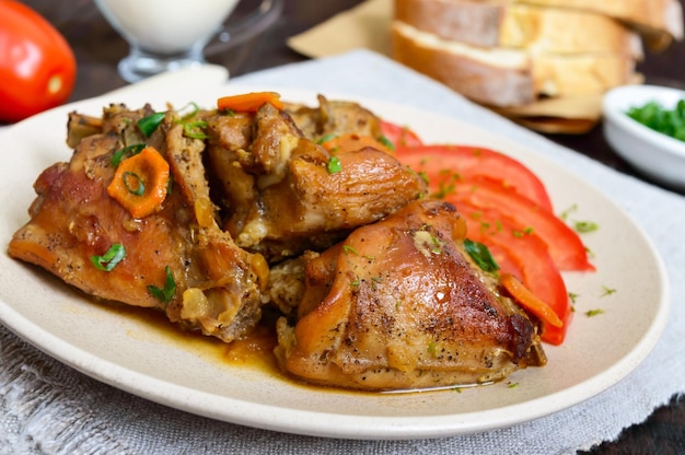 Geschmorte Kaninchenstücke mit frischen Tomaten auf einer Keramikplatte auf dunklem Holzhintergrund. Diätmenü. Nahaufnahme