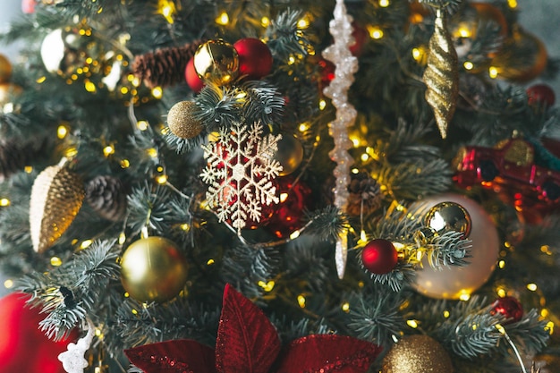 Geschmückter Weihnachtsbaum in goldenen und roten Spielzeugen mit dem strukturierten Hintergrund der Lichter Bokeh