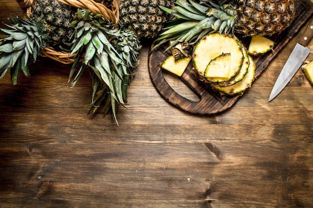 Geschnittene Ananas auf einem Schneidebrett mit einem Messer. Auf einem Holztisch.