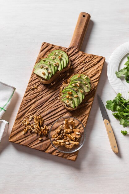 Geschnittene Avocado auf Toastbrot mit Nüssenfrühstück und Draufsicht des gesunden Lebensmittelkonzepts