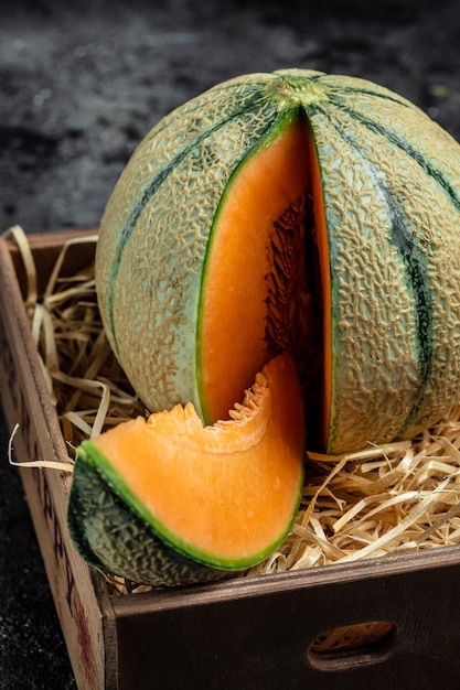 Foto geschnittene cantaloupe-melone rohe organische toskanische melone cantaloupe auf dunklem hintergrund vertikale bild draufsicht