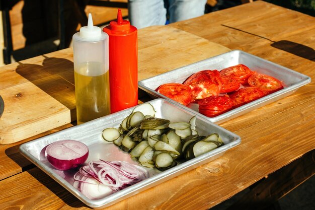 Geschnittene Gurken Tomaten in Aluminiumküvetten Zutaten zum Zusammenstellen von Hamburgern