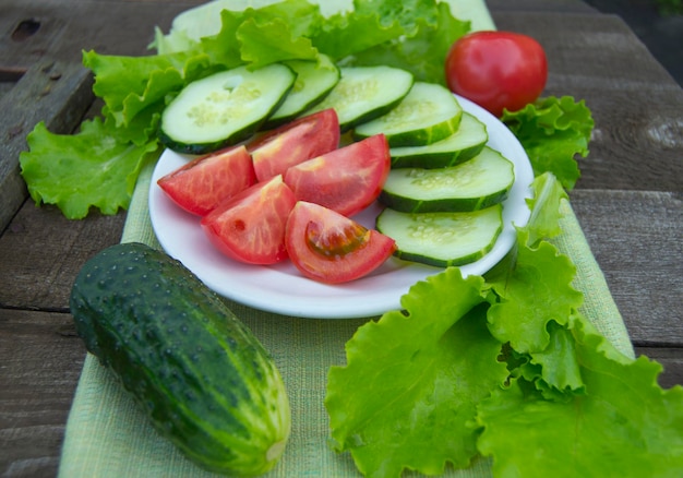 Geschnittene Gurken und Tomaten mit Kopfsalat auf altem Holztisch