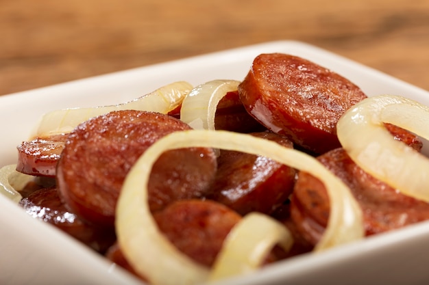 Geschnittene Kalabrese-Wurst mit Zwiebel auf Holzuntergrund