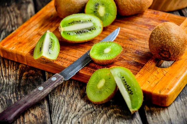 Geschnittene Kiwi auf einem Küchenbrett mit einem Messer auf einem Holztisch.