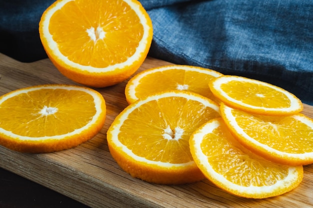 Geschnittene Orangenfrüchte in der Nähe von Denim-Textilien auf Holzbrett Orange saftige Frucht Zitrusfrüchte minimales Konzept