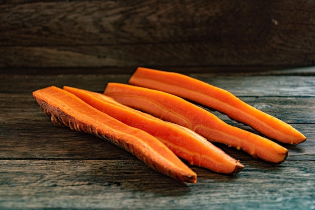 Geschnittene rohe süße Karotten auf einem hölzernen Küchentisch.
