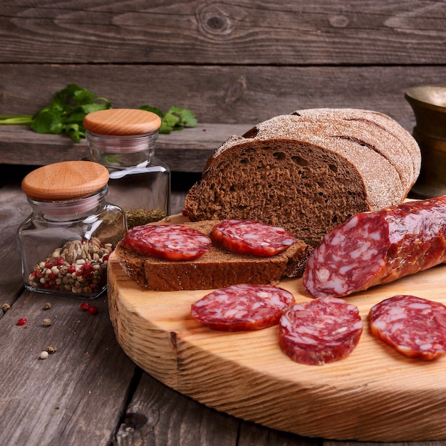 Geschnittene Salami und Brot auf einem Schneidebrett, quadratisches Foto