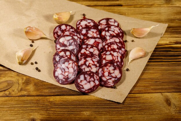 Geschnittene Salamiwurst auf braunem Papier auf Holztisch