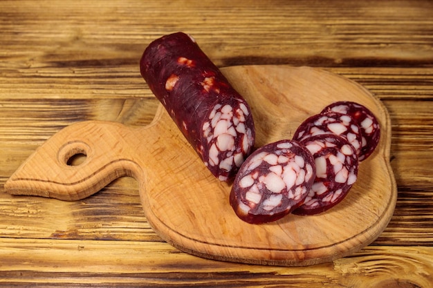 Geschnittene Salamiwurst auf Schneidebrett auf Holztisch
