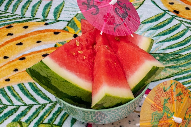 Geschnittene Wassermelone auf einem tropischen Hintergrund von Palmblättern.