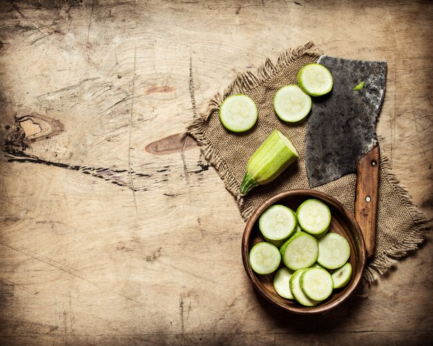 Geschnittene Zucchini und ein altes Beil. Auf hölzernem Hintergrund.