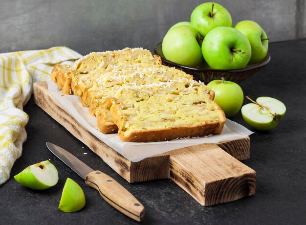 Geschnittener Apfel-Kokos-Oaf-Kuchen auf Holzbrett auf dunklem Hintergrund