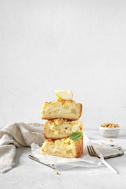 Geschnittener Apfelkuchen aus Mürbeteig mit Puddingcreme liegen in einem Haufen auf hellem Hintergrund ap