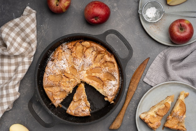 Geschnittener Apfelkuchen in einer gusseisernen Form auf dem Tisch. Draufsicht.