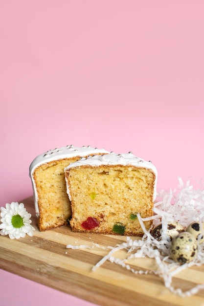 Foto geschnittener fruchtkuchen mit glasur oben, geschmückt mit kandierten früchten auf einem holzbrett