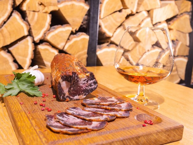 Geschnittener geräucherter Schinken auf einem Holztisch mit frischen Kräutern und aromatischen Gewürzen