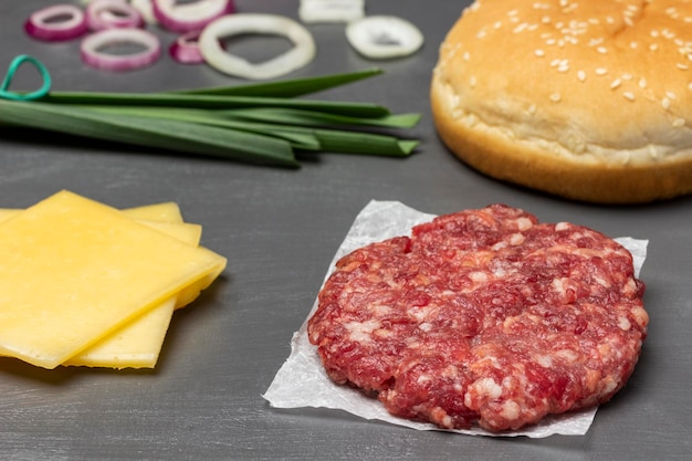 Geschnittener Käse-Rohburger auf Sesambrötchen aus Papier und Frühlingszwiebeln auf dem Tisch