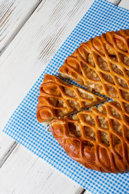 Geschnittener Kuchen auf einer Serviette. Gebackenes Produkt auf Holzhintergrund. Neues Rezept für traditionelles Gebäck. Saftige Apfelfüllung.