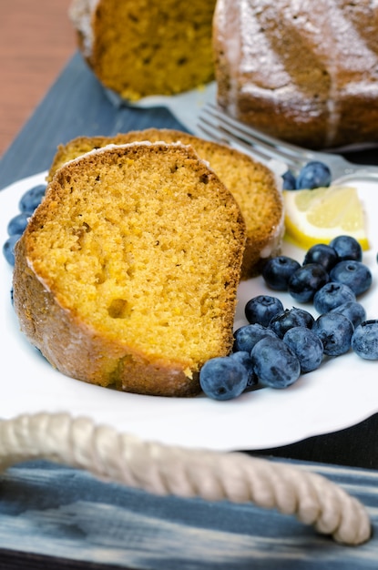 Geschnittener Zitronenkuchen mit Blaubeeren auf hölzernem Behälter