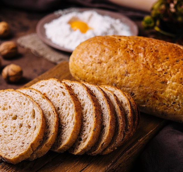 Geschnittenes Brot an Bord und Mehl mit frischem Ei