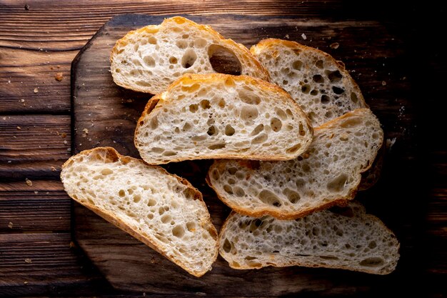 Geschnittenes Brot auf einem Brett. Auf einem Holztisch. Ansicht von oben.