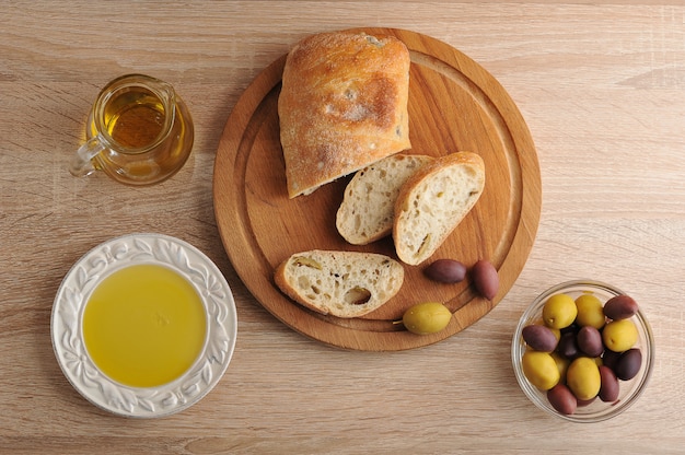 Geschnittenes Brot Ciabatta auf Runden Brett, Oliven und Olivenöl extra vergine