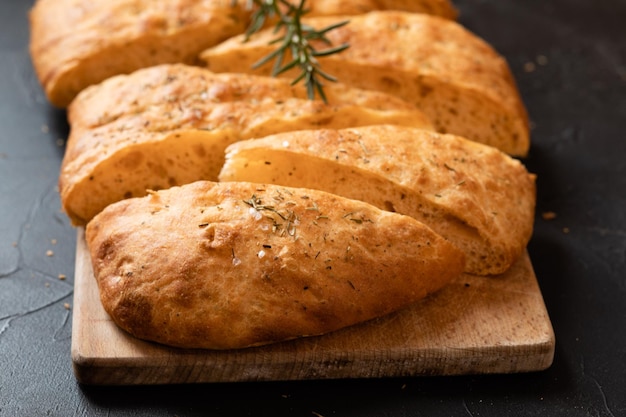 Geschnittenes Brot Ciabatta und Rosmarin auf Holzbrett