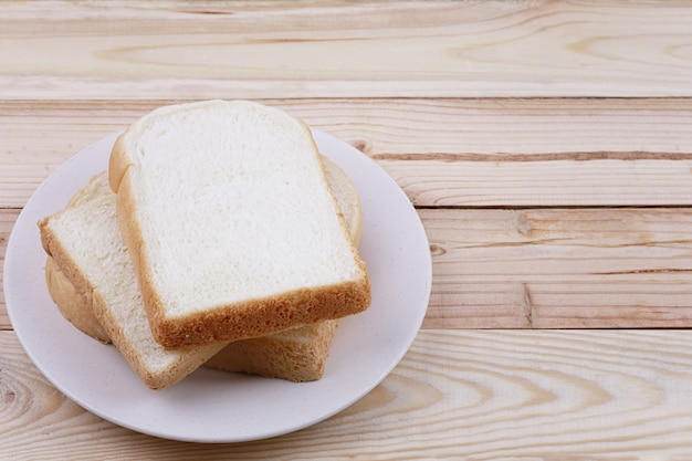 Geschnittenes brot gestapelt im teller auf bretterboden.