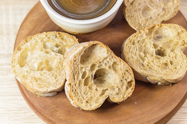 Geschnittenes Brot und ein Tasse Kaffee auf einem hölzernen Brett