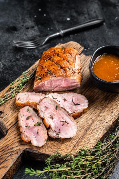 Geschnittenes Entenbrustfilet, gebratenes Steak mit Soße. Schwarzer Hintergrund. Ansicht von oben.